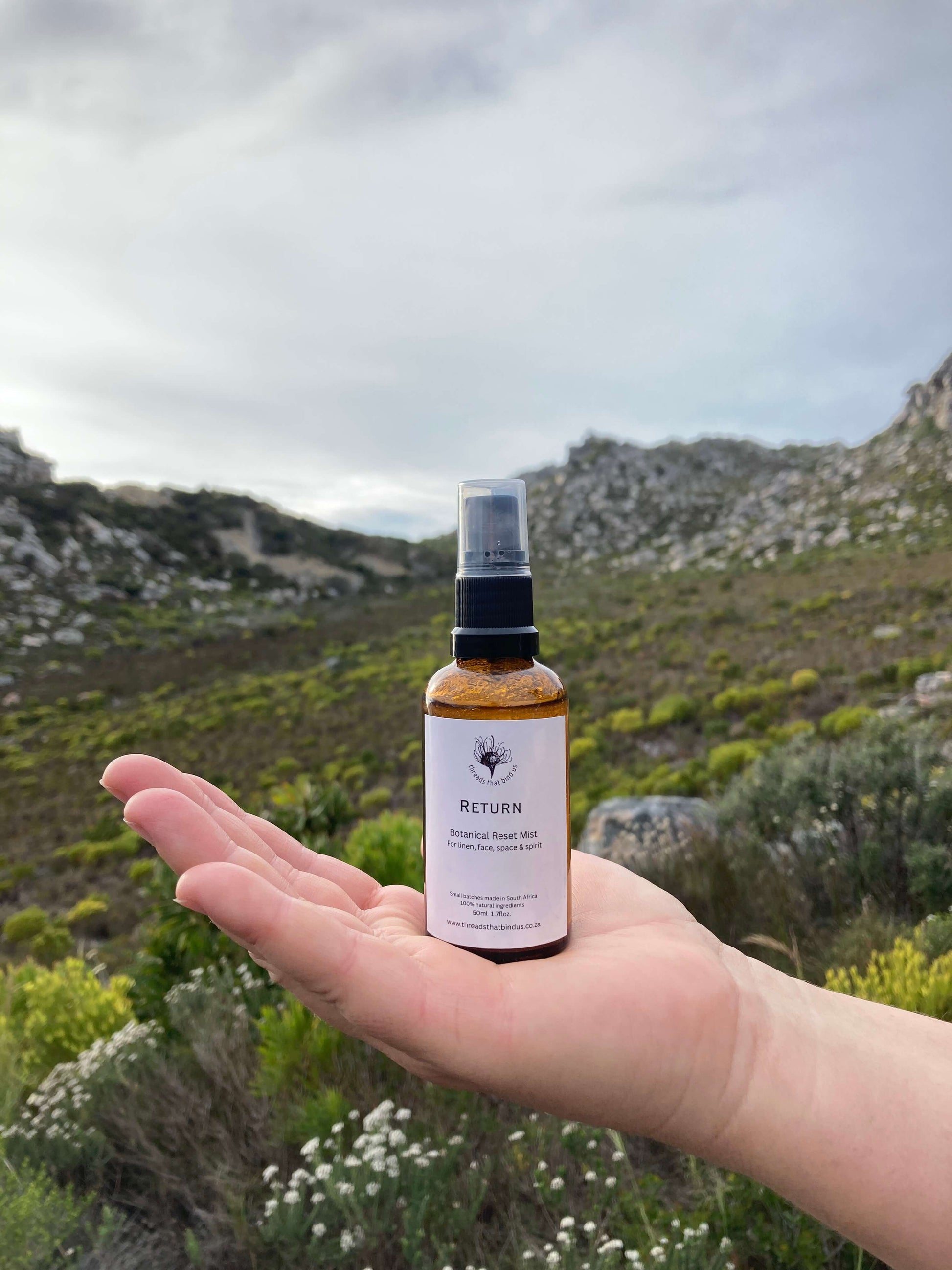 Hand holding a small bottle with a scenic background