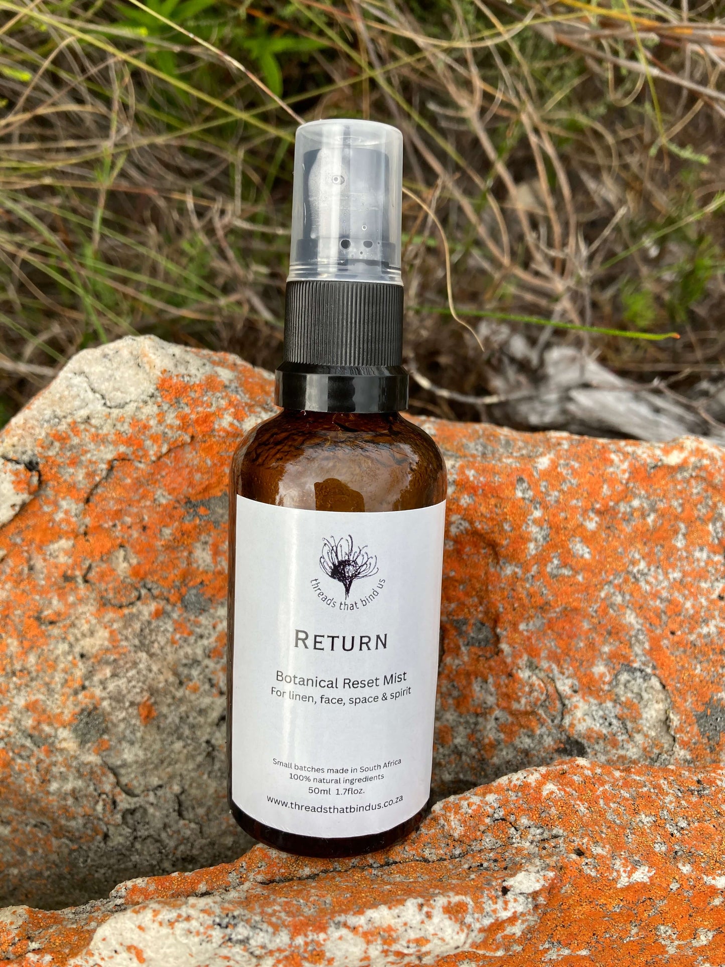 Bottle of 'Return' botanical reset mist on a textured rock surface with natural background